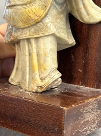 A Chinese partly polychromed soapstone figure on a wooden stand, 18th C.