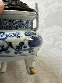 A Chinese blue and white tripod censer with floral design and a wooden cover, Ming
