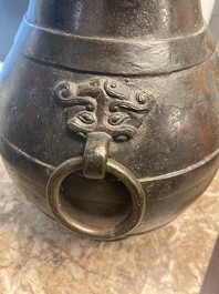 A Chinese bronze 'hu' vase with Han-style taotie handles on wooden stand, Ming