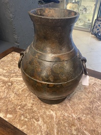 A Chinese bronze 'hu' vase with Han-style taotie handles on wooden stand, Ming