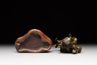 A Chinese bronze paperweight in the form of 'Shi De 拾得' on wooden stand, 16th C.
