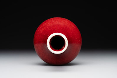 Two Chinese monochrome copper-red-glazed bottle vases on wooden stands, 19th C.