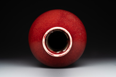Two Chinese monochrome copper-red-glazed bottle vases on wooden stands, 19th C.