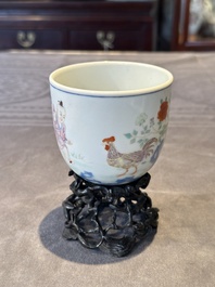 A Chinese famille rose cup with a boy and a rooster on wooden base, Qianlong mark, 20th C.
