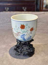 A Chinese famille rose cup with a boy and a rooster on wooden base, Qianlong mark, 20th C.