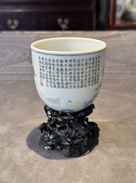 A Chinese famille rose cup with a boy and a rooster on wooden base, Qianlong mark, 20th C.