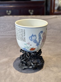 A Chinese famille rose cup with a boy and a rooster on wooden base, Qianlong mark, 20th C.