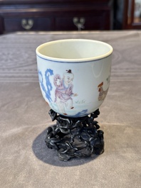 A Chinese famille rose cup with a boy and a rooster on wooden base, Qianlong mark, 20th C.