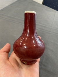 Two Chinese monochrome copper-red-glazed bottle vases on wooden stands, 19th C.