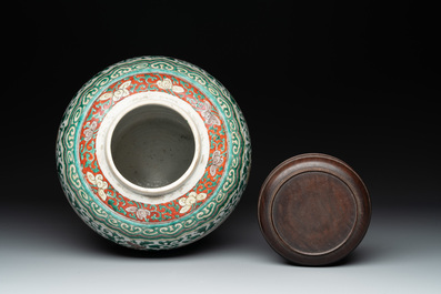 A Chinese famille verte jar with floral design and a wooden cover, Kangxi