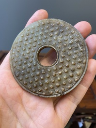 A Chinese russet jade 'bi' disc and a spinach-green flower-shaped pendant on wooden stands, Ming and Qing