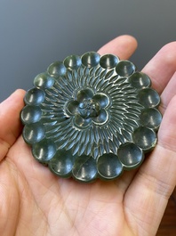 A Chinese russet jade 'bi' disc and a spinach-green flower-shaped pendant on wooden stands, Ming and Qing