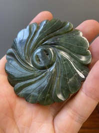 A Chinese russet jade 'bi' disc and a spinach-green flower-shaped pendant on wooden stands, Ming and Qing