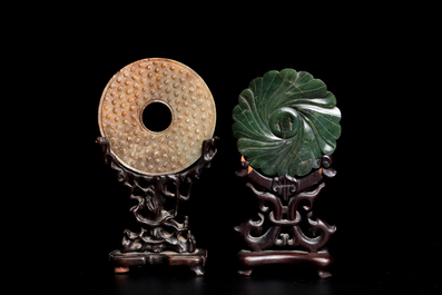 A Chinese russet jade 'bi' disc and a spinach-green flower-shaped pendant on wooden stands, Ming and Qing