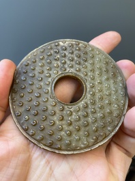 A Chinese russet jade 'bi' disc and a spinach-green flower-shaped pendant on wooden stands, Ming and Qing