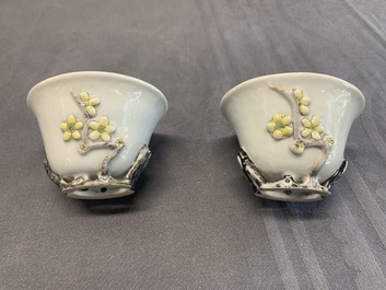 A pair of Chinese Dehua blanc de Chine relief-decorated famille rose 'prunus' cups, 19th C.