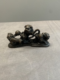 A rare Chinese bronze 'three dancing lions' paperweight or brush rest, Ming