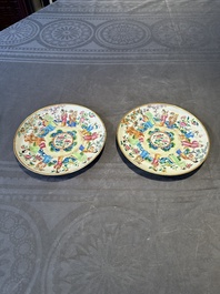A pair of Chinese Canton famille rose plates with figures in a garden, 19th C.