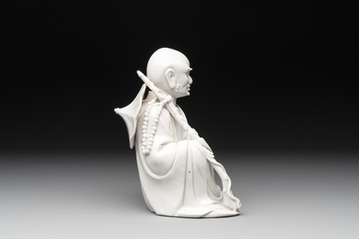 A Chinese Dehua blanc de Chine Luohan on wooden stand, 19/20th C.