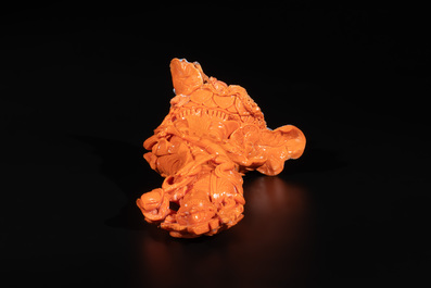 A Chinese red coral Guanyin holding a lotus on wooden stand, 19/20th C.