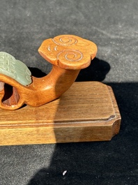 A Chinese pale celadon jade 'double happiness' hairpin on a ruyi-shaped wooden stand, 19th C.