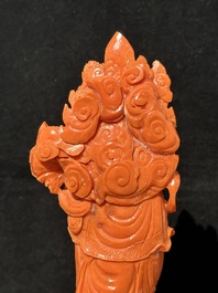 A Chinese red coral Guanyin holding a lotus on wooden stand, 19/20th C.