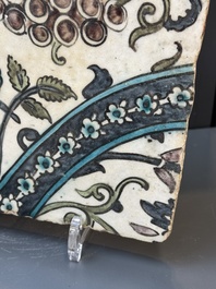 A Syrian Damascus Iznik-style tile with grape and flower scrolls, early 17th C.