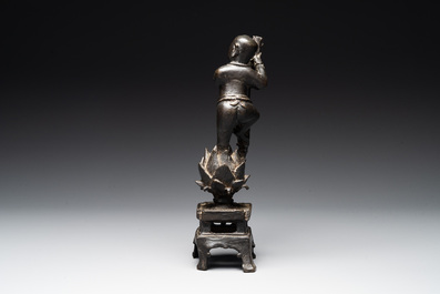 A Chinese bronze incense holder of a boy standing on a lotus, Ming