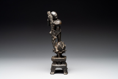 A Chinese bronze incense holder of a boy standing on a lotus, Ming
