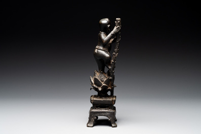 A Chinese bronze incense holder of a boy standing on a lotus, Ming