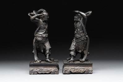 A pair of Chinese bronze guardians on stands, 17/18th C.
