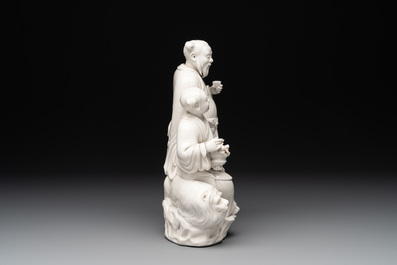A Chinese Dehua blanc de Chine group of a man and a seated boy on a lion, 20th C.
