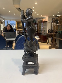 A Chinese bronze incense holder of a boy standing on a lotus, Ming