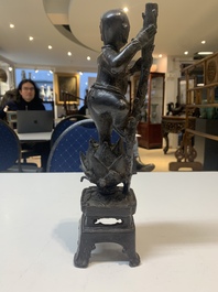 A Chinese bronze incense holder of a boy standing on a lotus, Ming