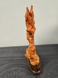A Chinese pink-orange coral group of a goddess of spring, a wise man and children in a pine tree, 19/20th C.