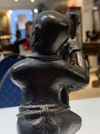 A Chinese bronze incense holder of a boy standing on a lotus, Ming