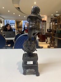 A Chinese bronze incense holder of a boy standing on a lotus, Ming