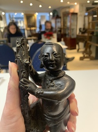 A Chinese bronze incense holder of a boy standing on a lotus, Ming