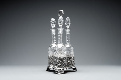 A sterling silver tantalus with three crystal-cut bottles and stoppers, 19/20th C.
