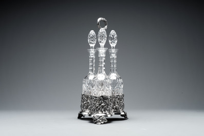 A sterling silver tantalus with three crystal-cut bottles and stoppers, 19/20th C.