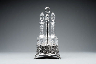 A sterling silver tantalus with three crystal-cut bottles and stoppers, 19/20th C.