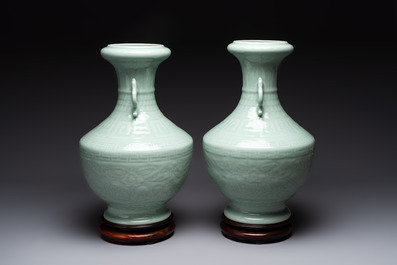 A pair of Chinese celadon-glazed vases with 'anhua' design on wooden stands, Qianlong mark, 19th C.