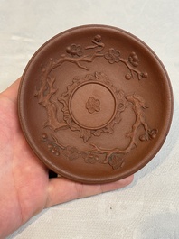A Chinese Yixing stoneware cup and saucer with plum blossom relief design, Kangxi