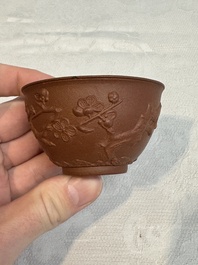 A Chinese Yixing stoneware cup and saucer with plum blossom relief design, Kangxi