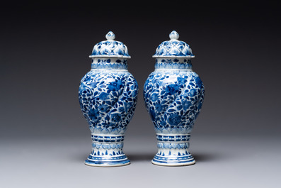 A pair of Chinese blue and white vases and covers with floral design, Kangxi