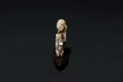 A Chinese celadon and russet jade figure of a boy riding a dragon carp, Qing