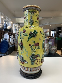 A pair of Chinese famille rose yellow-ground relief-decorated vases with wooden stands, 19th C.