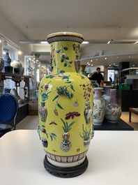 A pair of Chinese famille rose yellow-ground relief-decorated vases with wooden stands, 19th C.