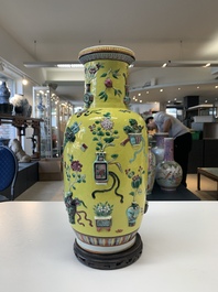 A pair of Chinese famille rose yellow-ground relief-decorated vases with wooden stands, 19th C.
