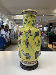 A pair of Chinese famille rose yellow-ground relief-decorated vases with wooden stands, 19th C.